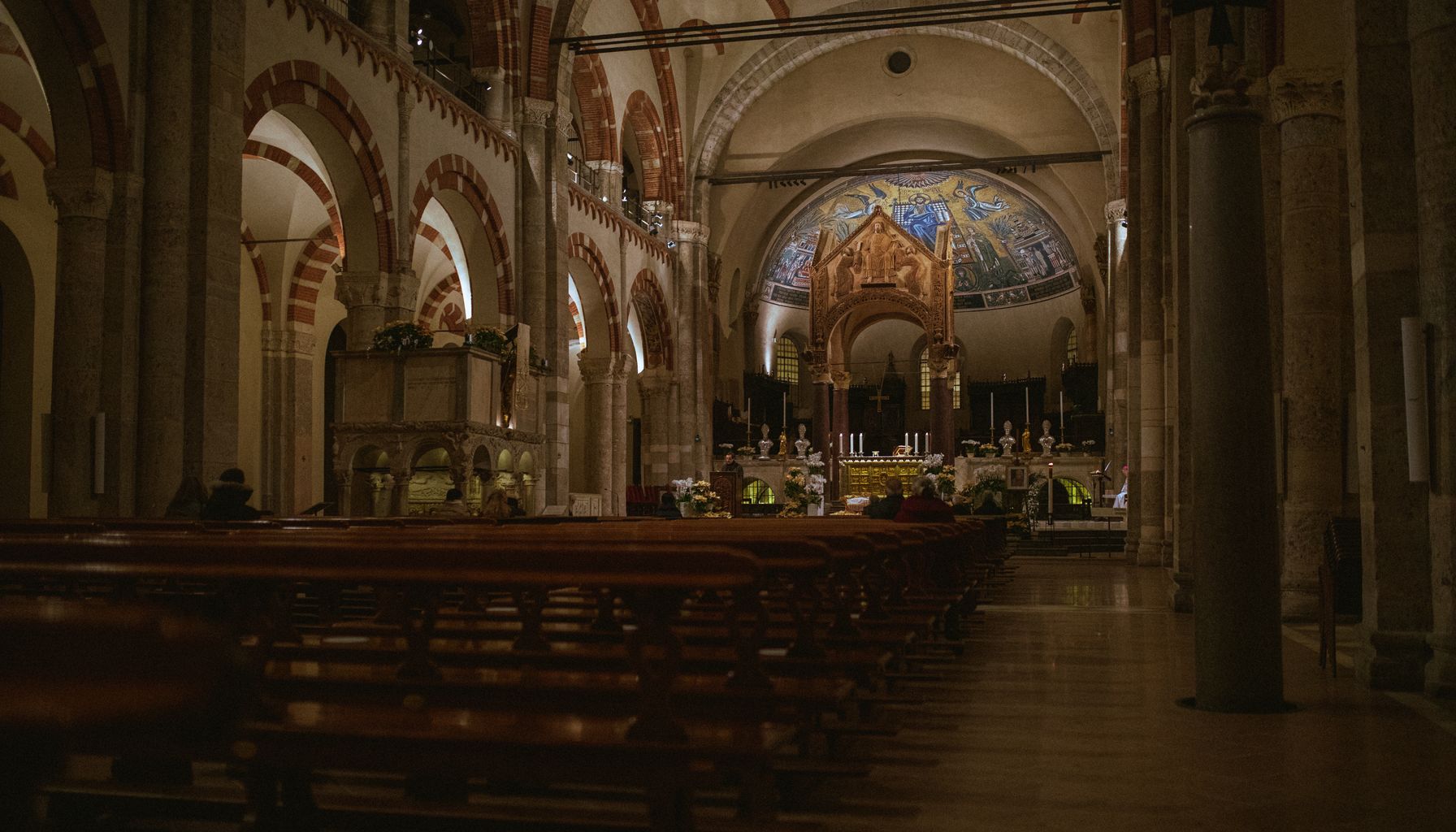Ornate interior of a historic basilica in Milan with intricate arches and altar.