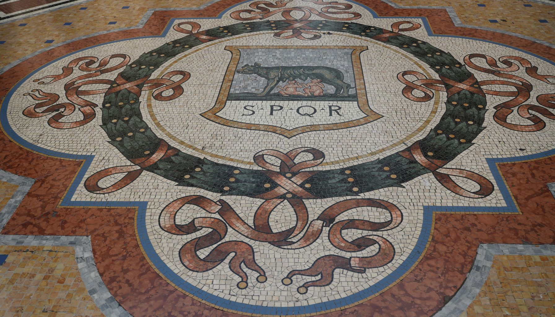 Intricate Roman mosaic floor featuring SPQR emblem and traditional Italian motifs, rich in cultural heritage.
