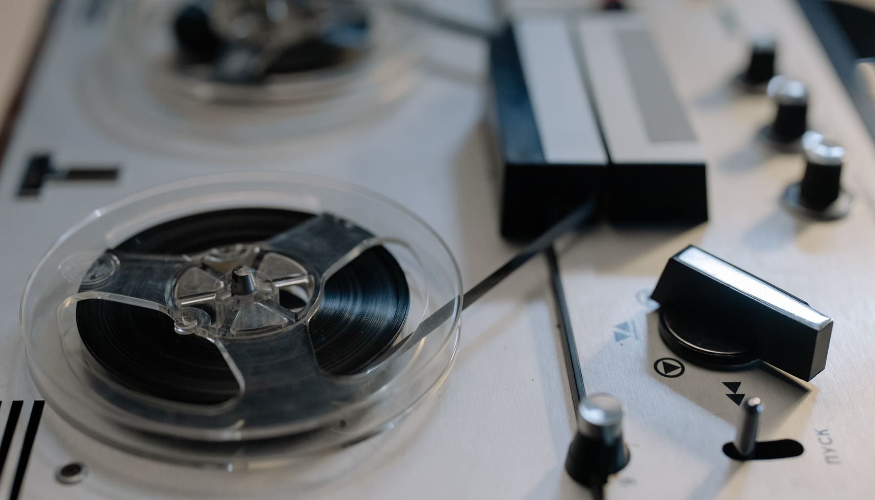 Close-up view of a classic reel-to-reel tape recorder with knobs and tapes.