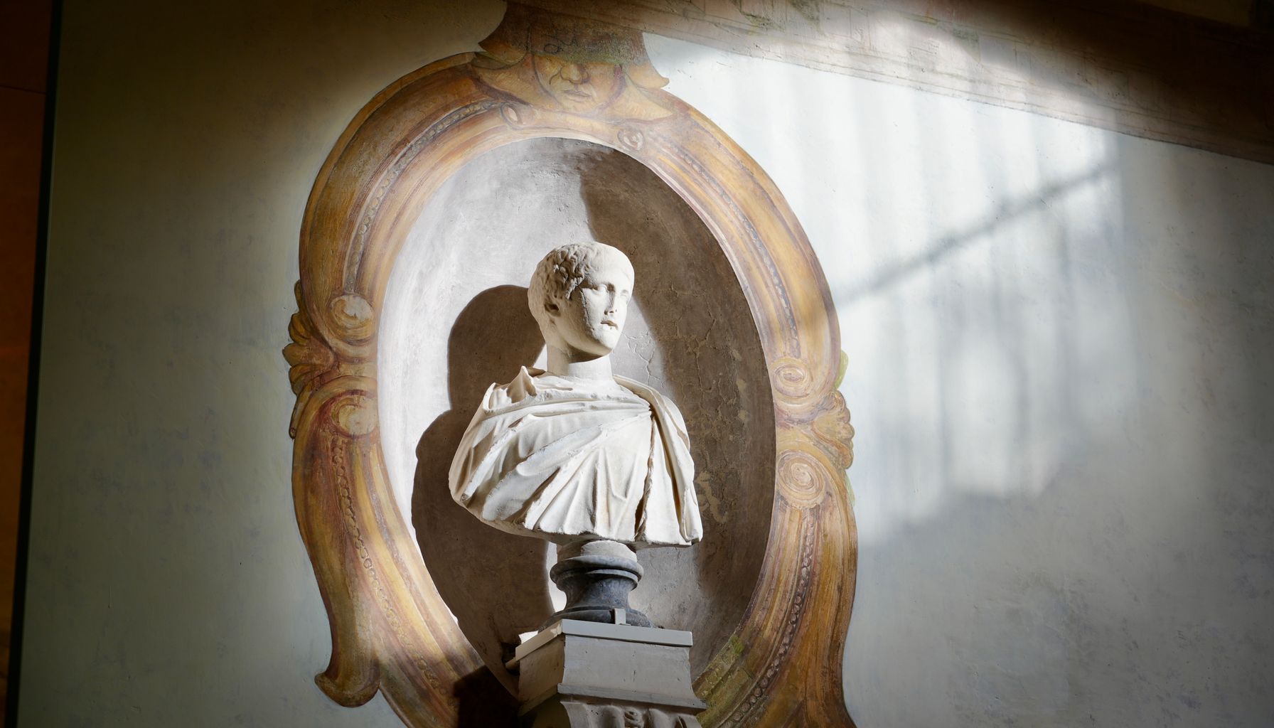 Ornate marble bust displayed in Roman museum, bathed in soft sunlight.