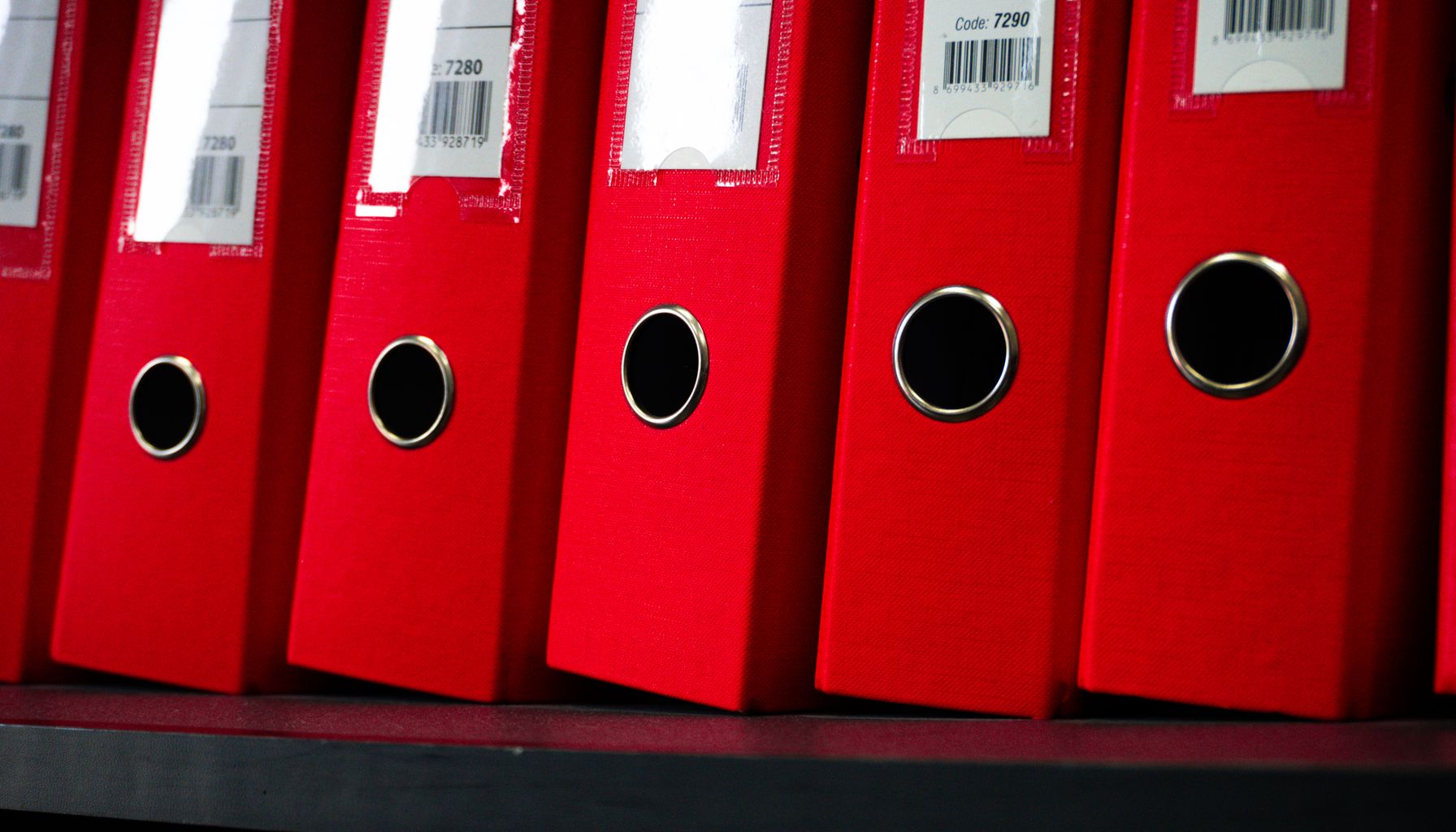 Close-up view of red office binders neatly organized on a shelf.