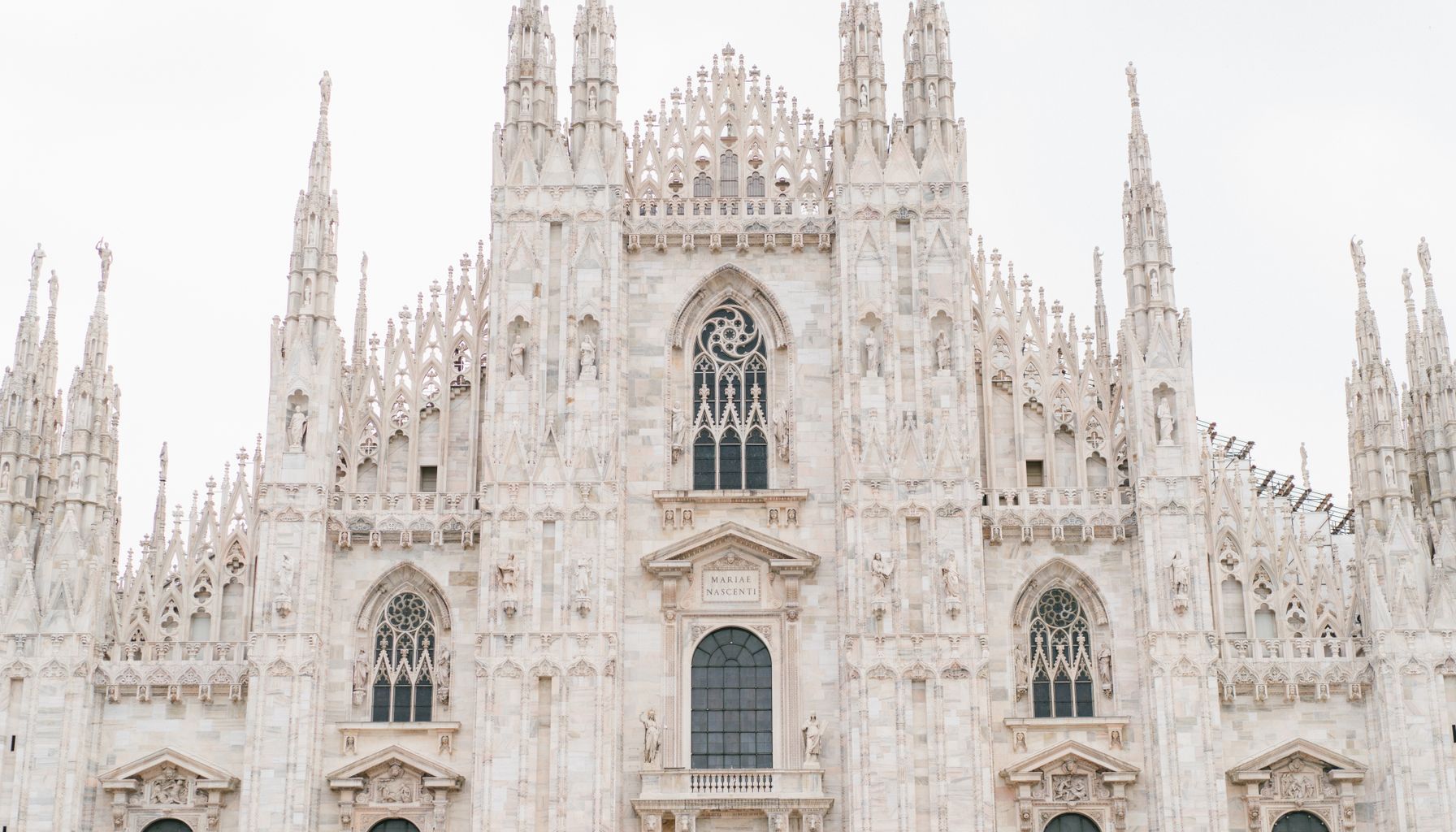 Facade of medieval cathedral with carved elements sculptures stained glass windows and spires
