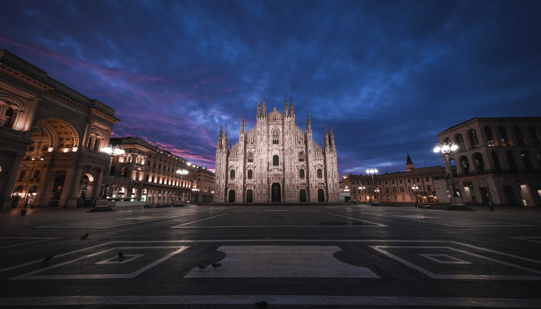 Low angle of aged masonry church exterior near square and buildings under bright sky in evening in Italy