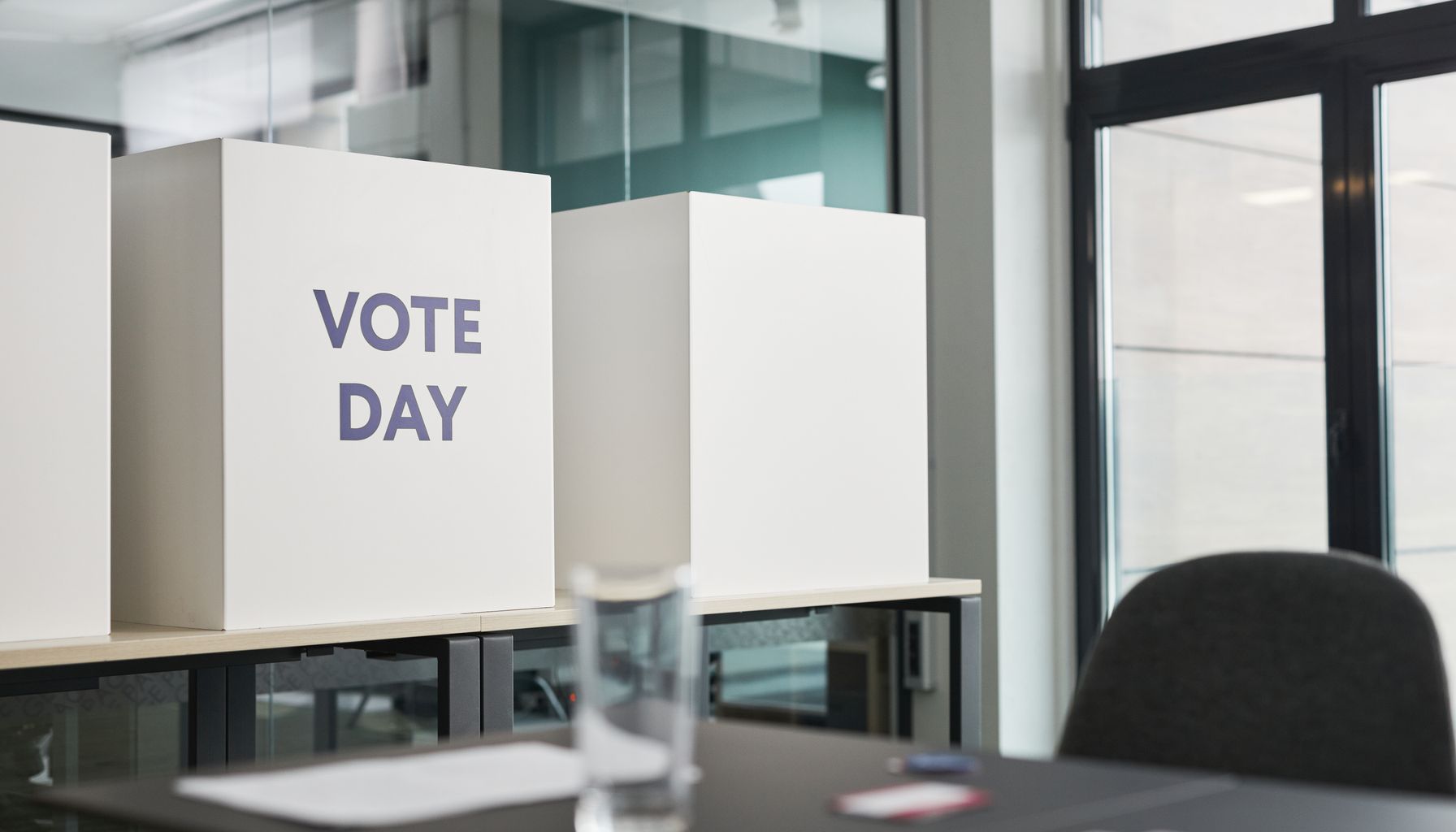 A modern office with voting booths labeled 'Vote Day' indicating election activity.