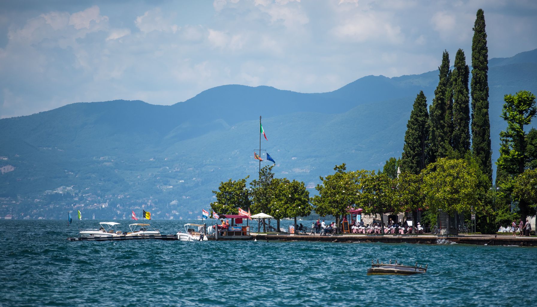 A picturesque Italian lakeside scene with boats and mountains, perfect for a summer getaway.