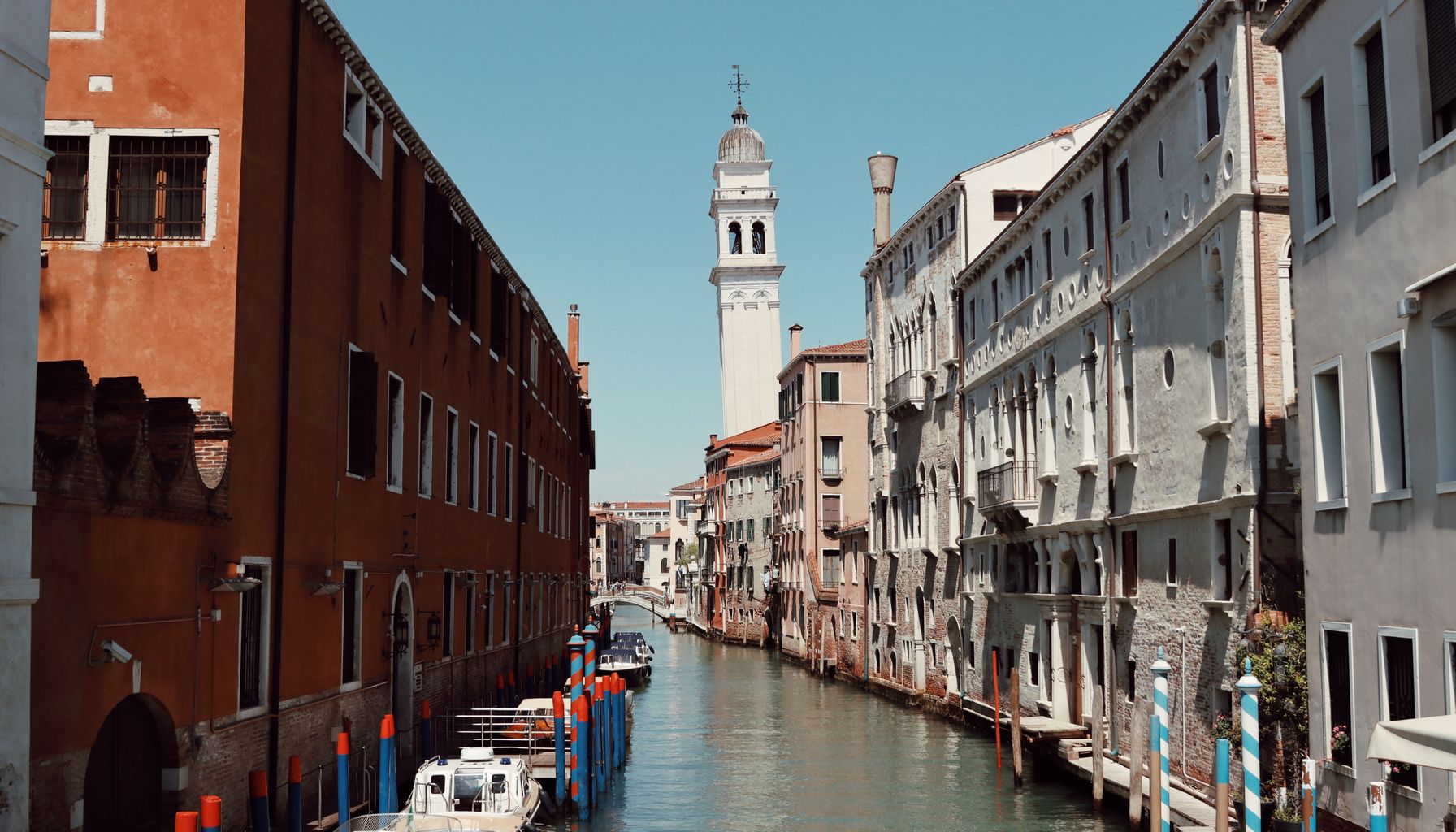 Charming view of a narrow canal in Venice surrounded by historic architecture, perfect for travel enthusiasts.