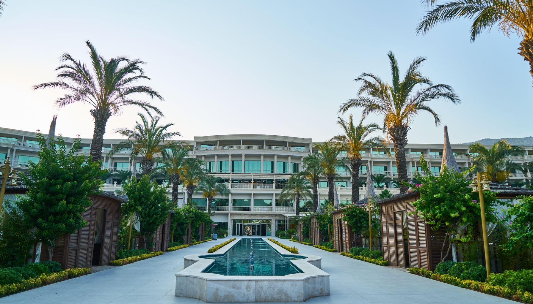 Explore a stunning modern resort featuring a sleek swimming pool surrounded by palm trees.