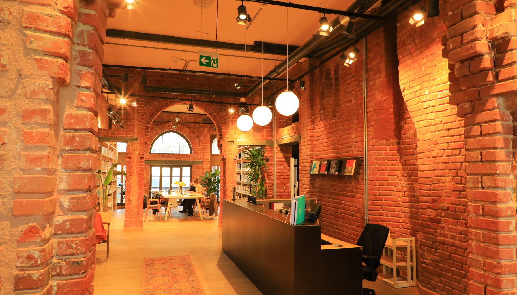 Warm interior of a public library in Istanbul featuring exposed brick walls and modern lighting.