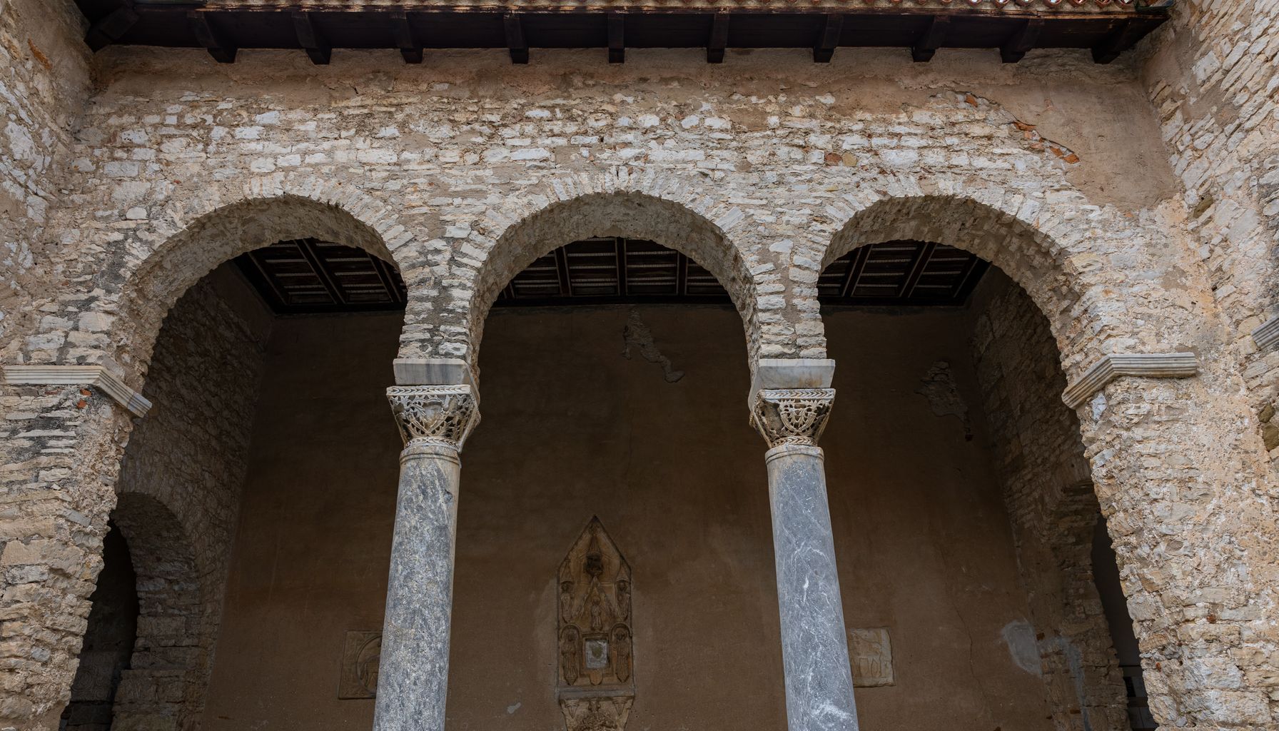 Historic cloister of the Euphrasian Basilica, showcasing ancient stone arches and columns.