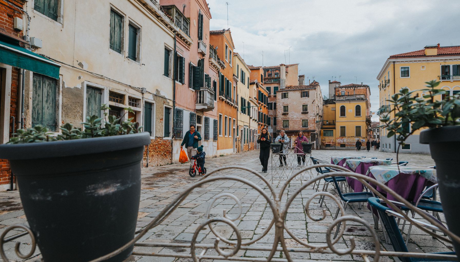 Charming Venetian street with colorful buildings and people enjoying a leisurely stroll.