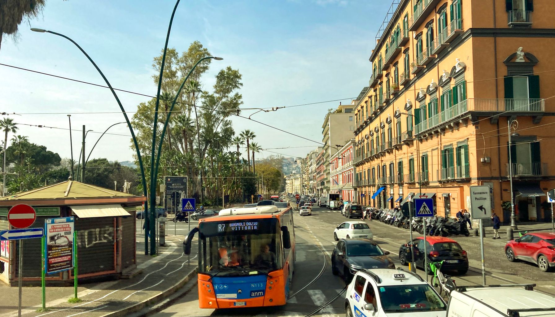 Street view of daily life in Naples with tram, traffic, and historical buildings.