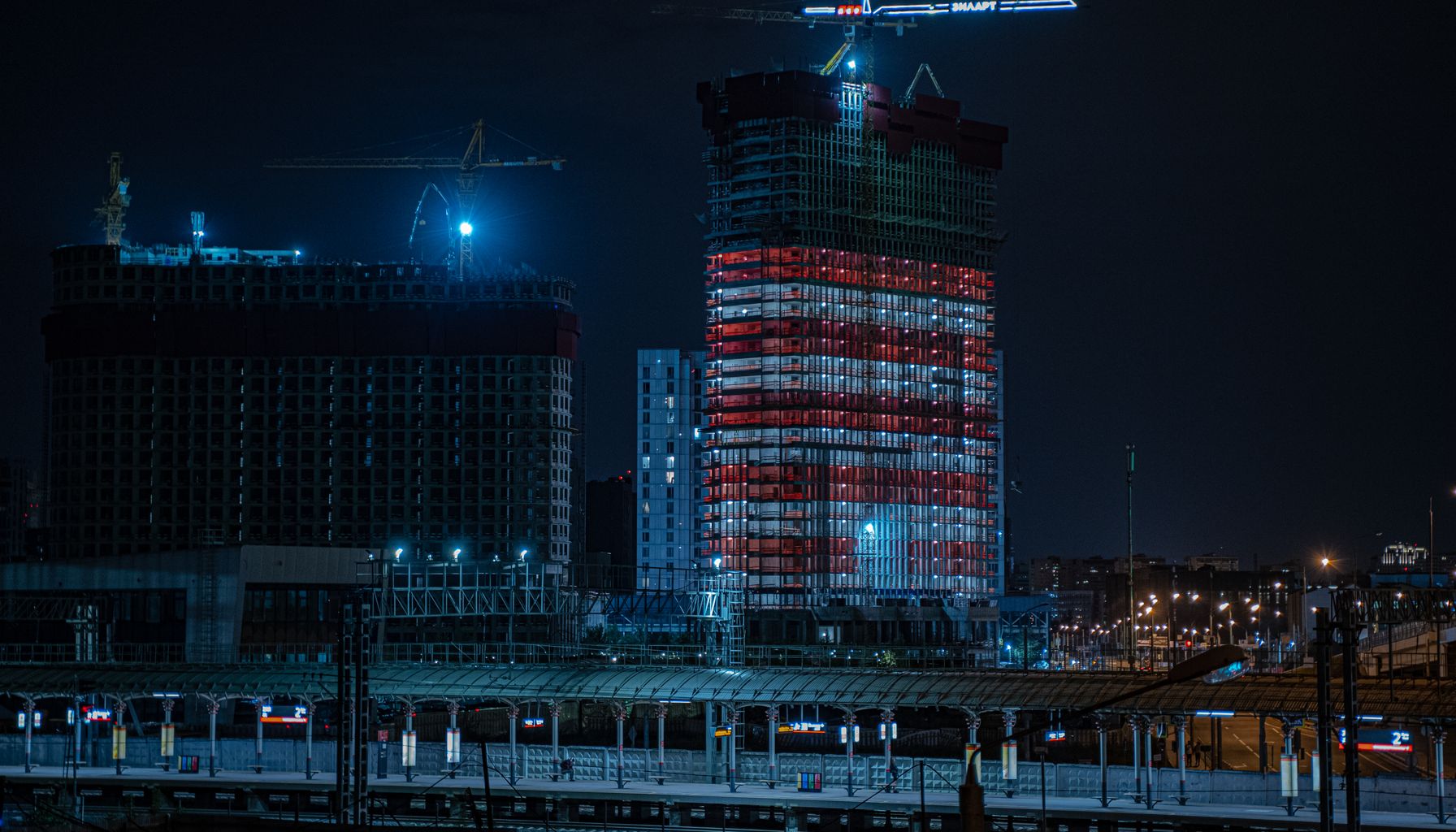 Illuminated city at night showcasing a construction site with building cranes.
