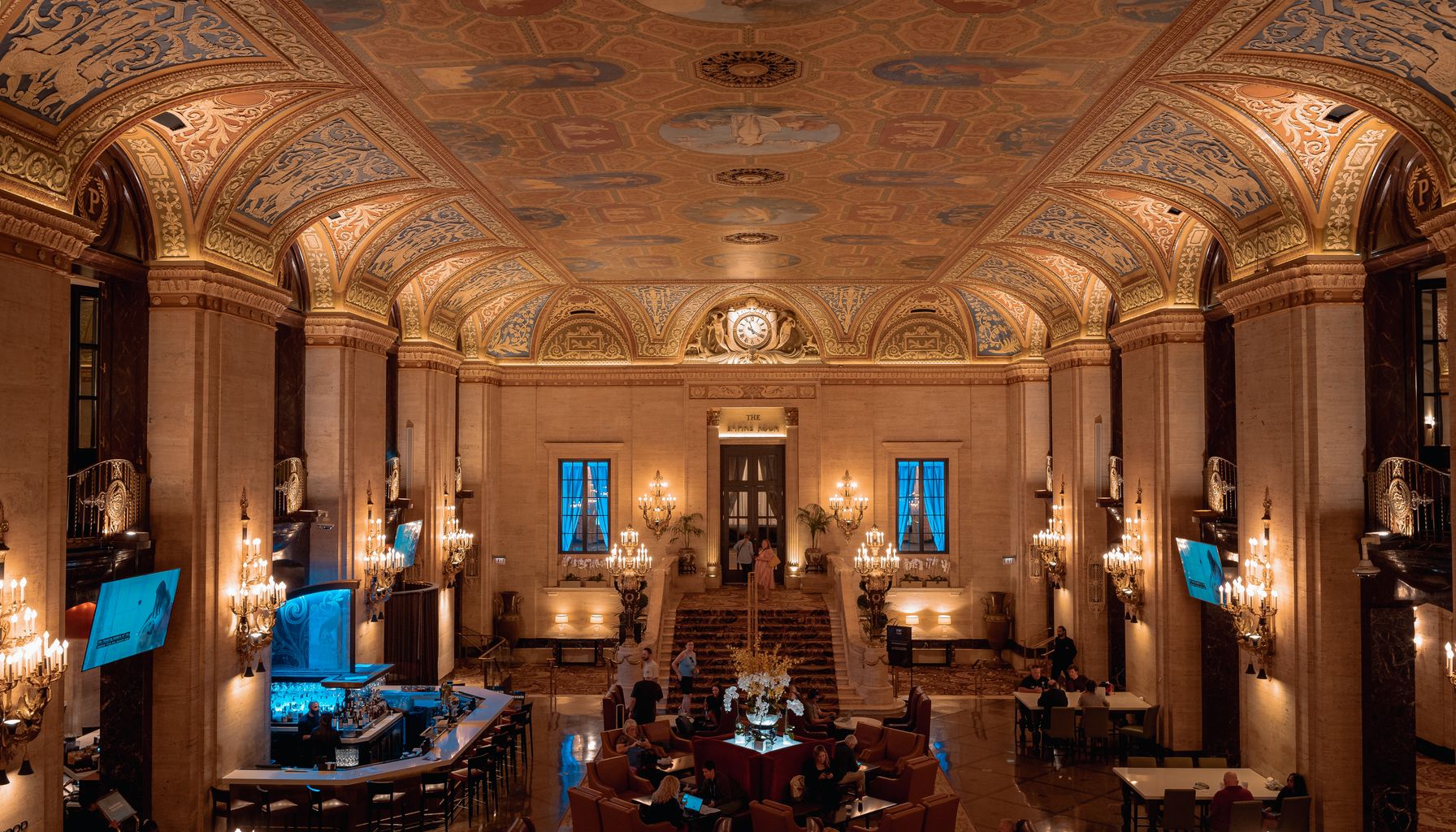 Luxurious hotel lobby with ornate ceiling and elegant chandeliers.