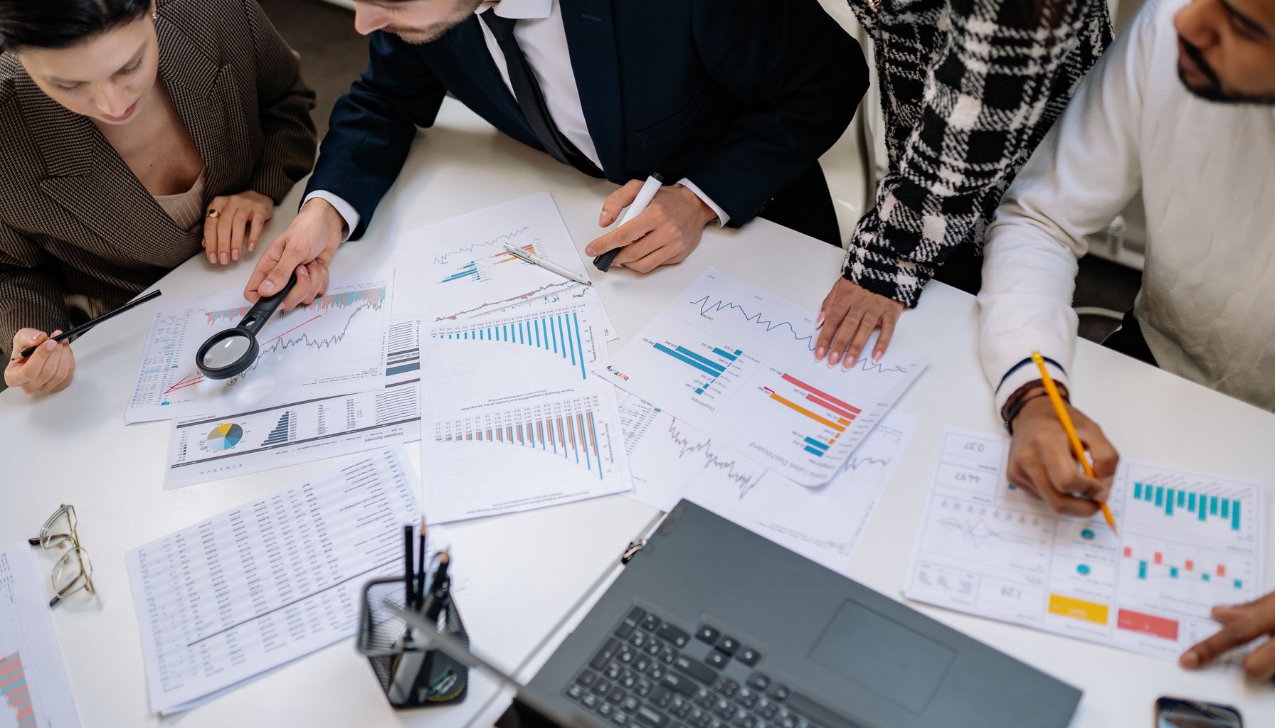 A group of professionals reviewing financial charts in an office meeting setting.