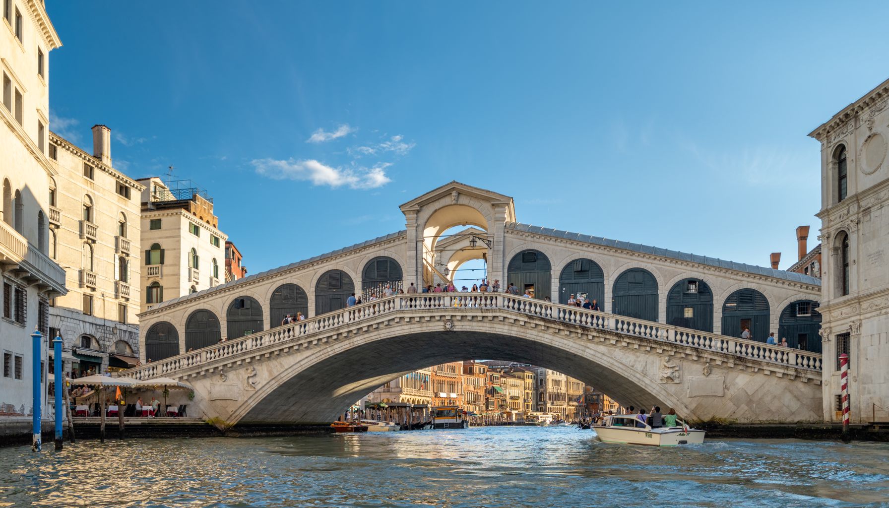 Scenic view of Rialto Bridge with gondolas on the Grand Canal in Venice, Italy, during a sunny day.