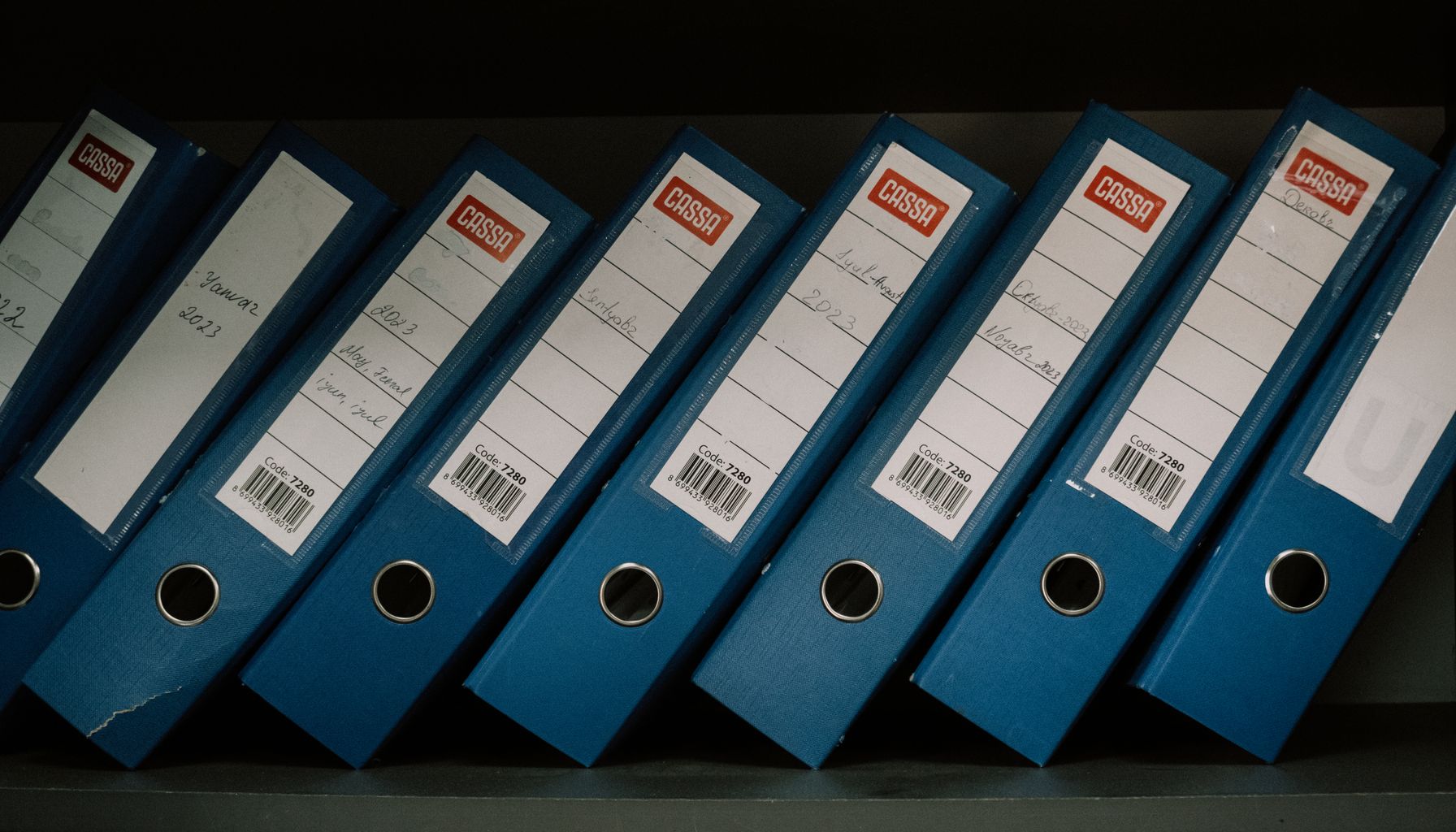 Neatly arranged blue office binders labeled with dates and names for organized storage.