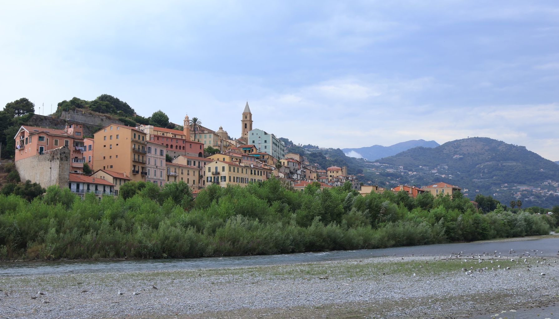 Picturesque hillside town on the Italian Riviera with colorful buildings under a cloudy sky.