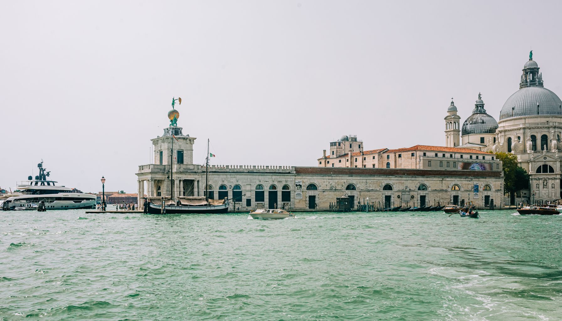 Beautiful view of Punta della Dogana and Basilica di Santa Maria della Salute in Venice with boats on the canal.
