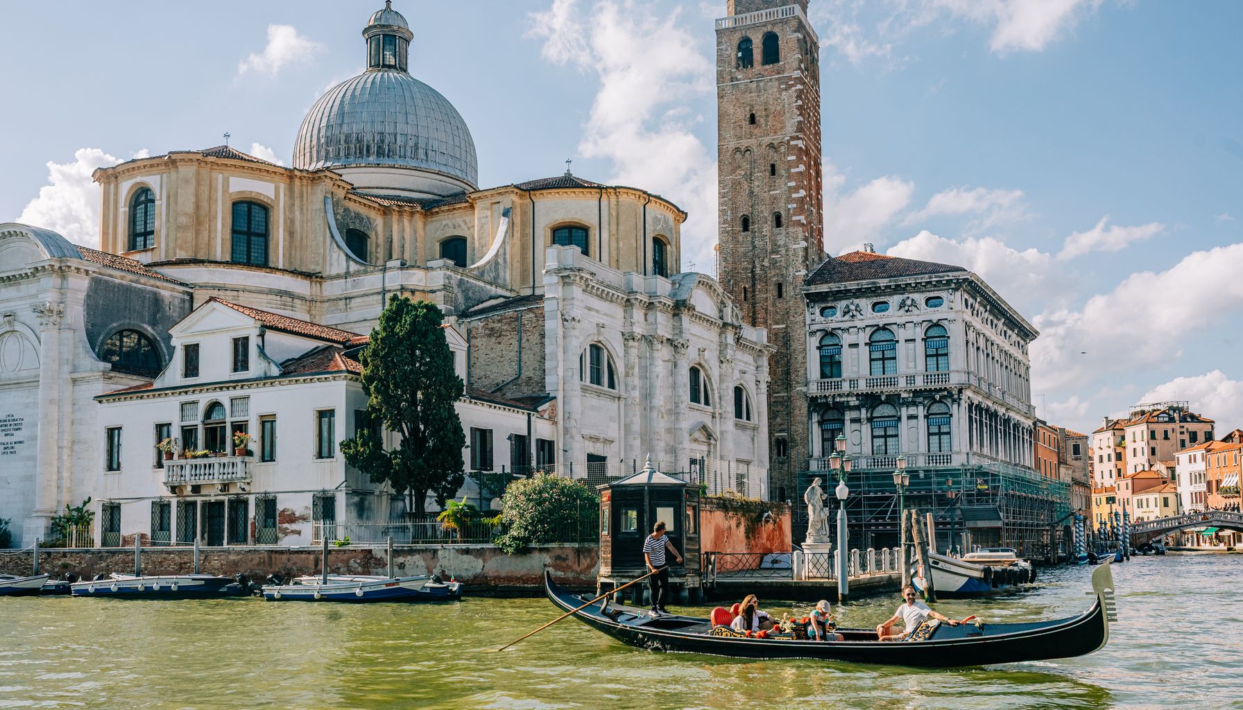 Experience a classic gondola ride on a sunny day in the iconic canals of Venice, Italy.