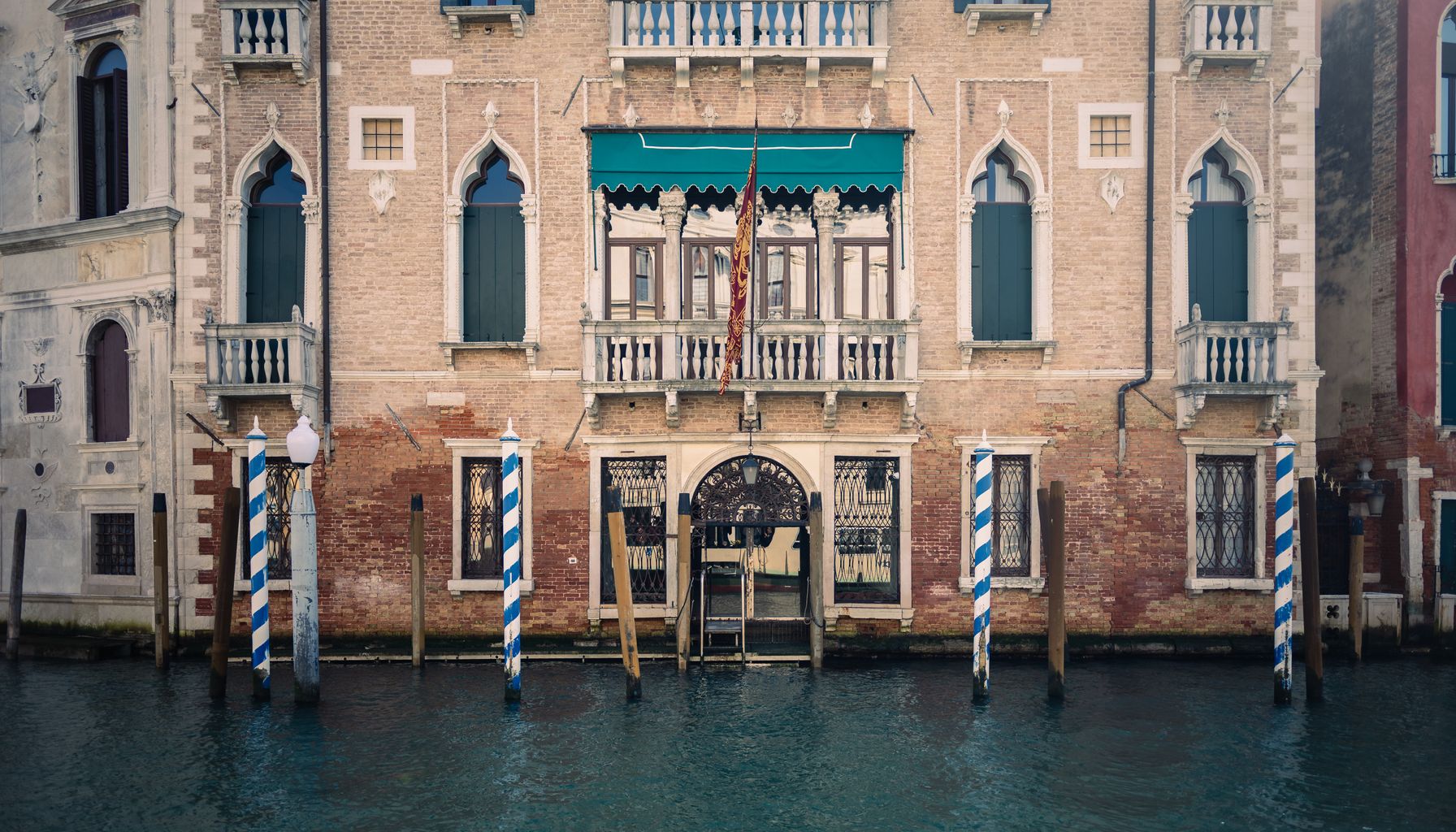 Charming Venice canal scene with classic architecture, water, and striped poles.