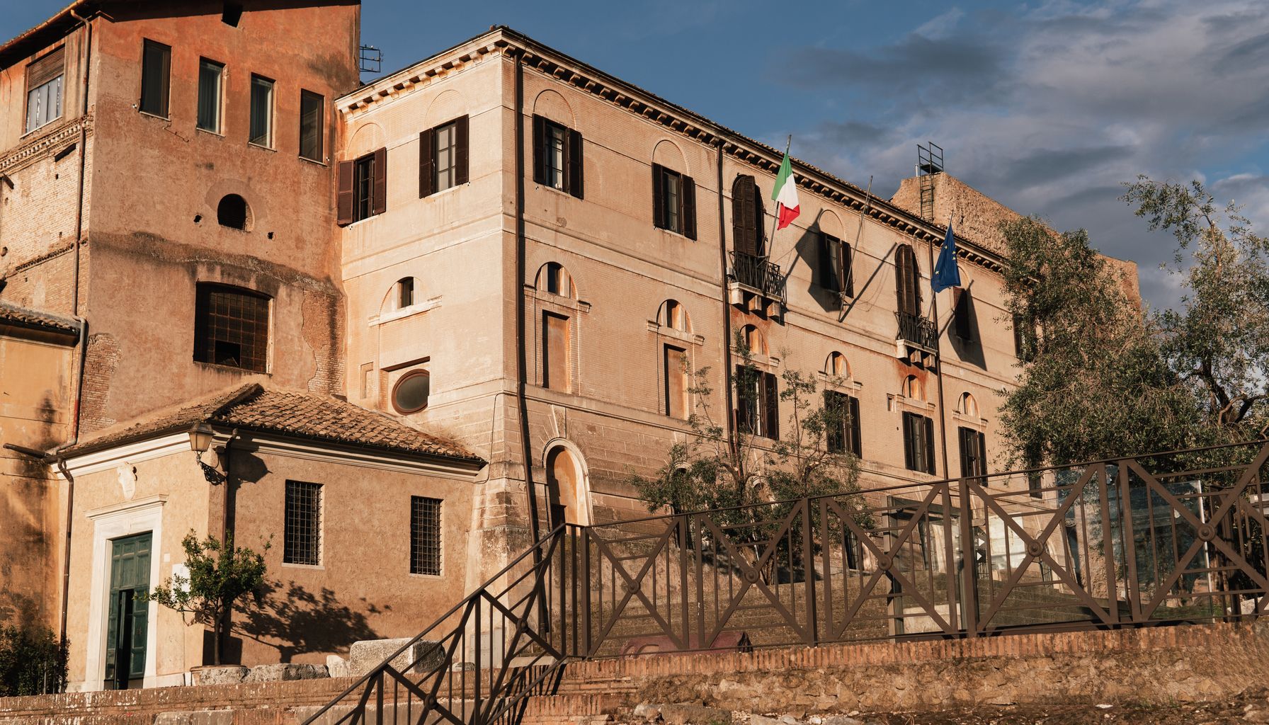 Sunlit historic building in Rome's Lazio region with Italian flags.