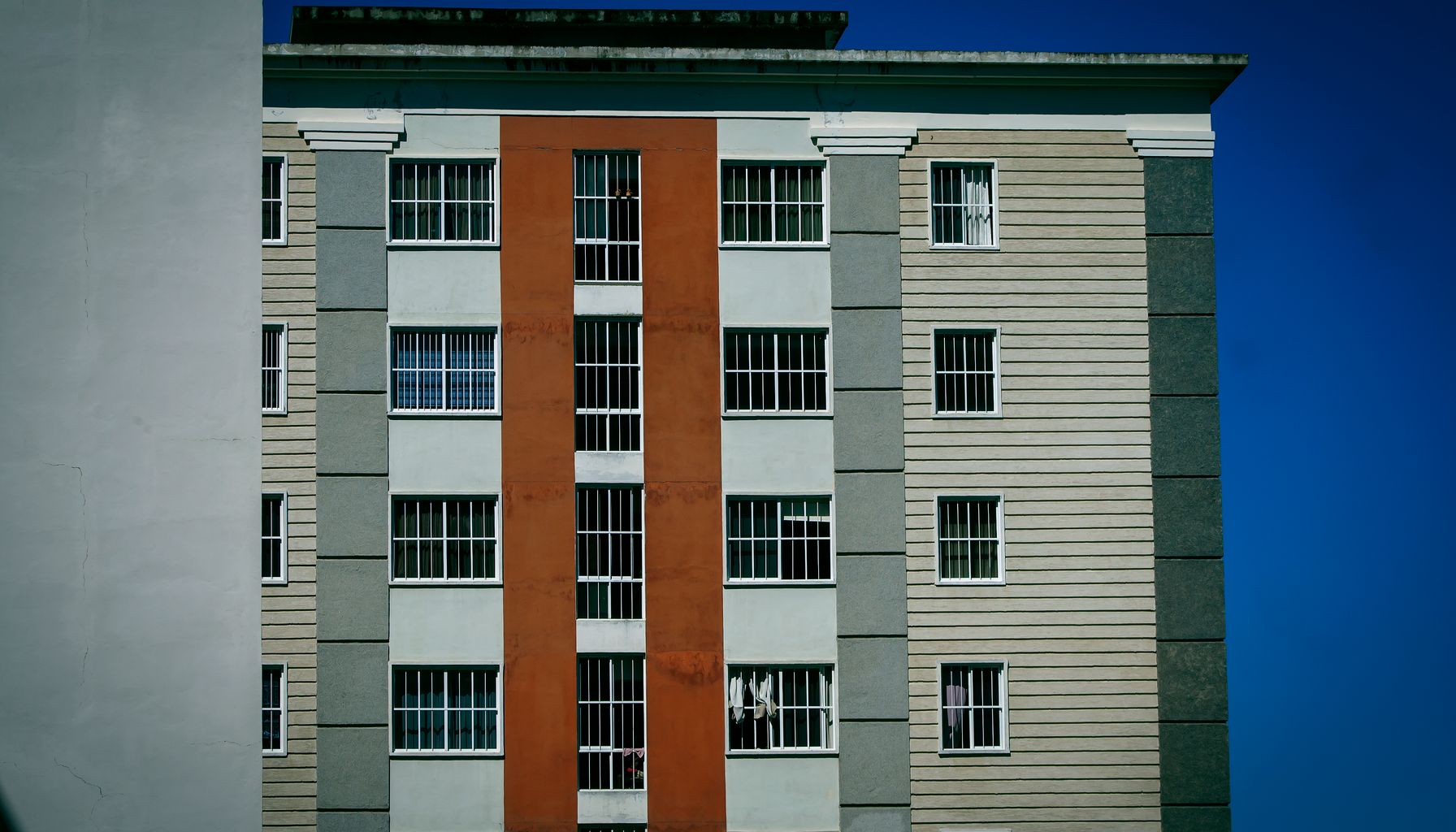 Facade of a modern high-rise building with colorful design against a clear blue sky.