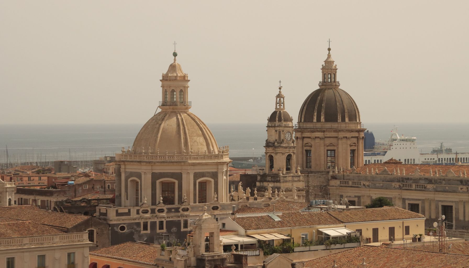 Impressive aerial shot of Catania Cathedral domes overlooking the sea in Sicily, Italy.
