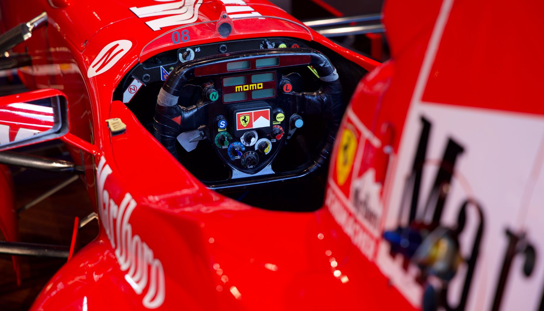 Vibrant red Formula 1 car cockpit, showcasing steering wheel and intricate details.